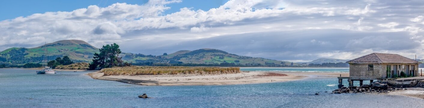 Sandbank am Waikouaiti Flussmuendung mit Segelboot und historischem Bootshaus bei Karitane Neuseeland