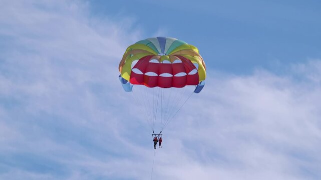 Thrilling experience of parasailing, offering tourists a breathtaking view from the sky, over the sparkling sea in 4k slow motion 60fps