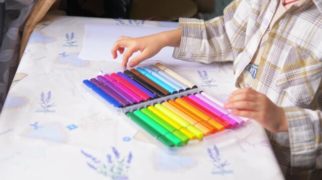 happy young boy proudly showing an organized plastic case of colorful markers for drawing
