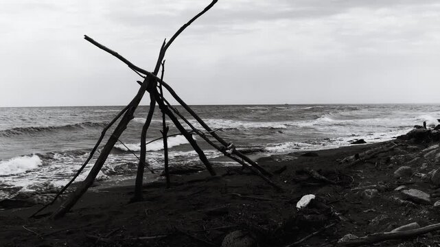 A black and white  of a teepee on the beach, great for travel or outdoor lifestyle scenes