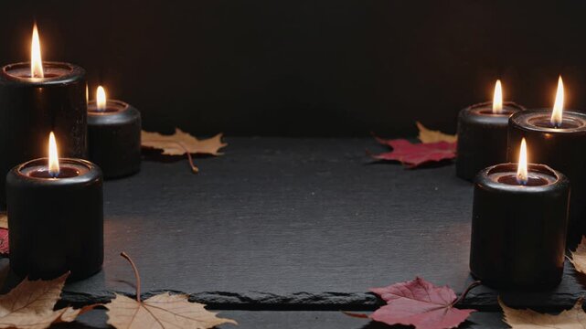 Black burning candles with autumn leaves frame