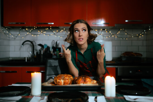Hopeful Housewife Crossing Fingers Wishing For Perfect Christmas Roast Dinner. Anxious young woman hoping holiday meal turns out well standing in kitchen