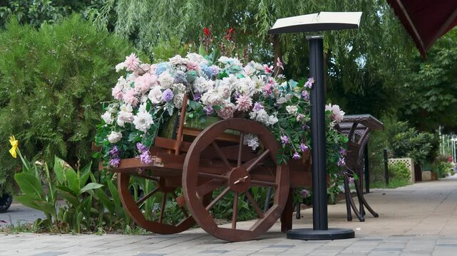 A colorful wagon filled with flowers sits on the sidewalk, perfect for a market or parade display