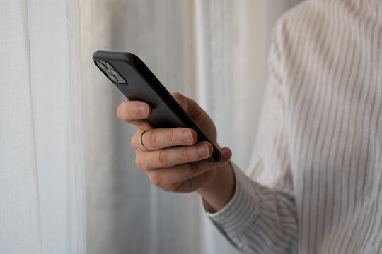 Man using smartphone at home, close up of hand holding mobile phone, online communication, texting, internet and modern digital technology concept
