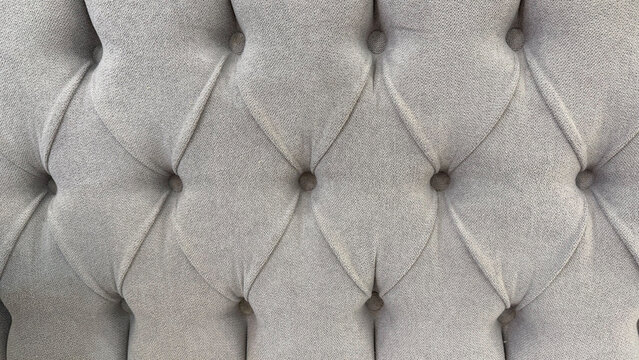 Close-up of elegant beige tufted upholstery with deep button detailing and geometric diamond pattern, soft textile texture for interior design.