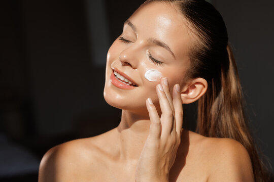 Face cream application with young woman enjoying skincare routine