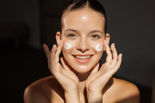 Face cream application skincare routine with smiling young woman