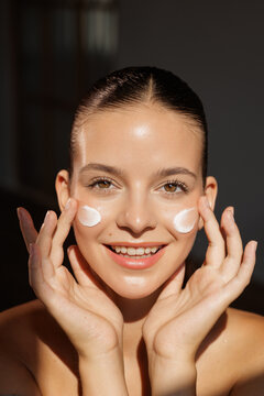 Smiling Woman Applying Facial Cream for Radiant Skin