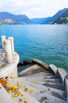 Beautiful promenade of Como lake, Italy. Clouds over the Alps mountains at cloudy day. Autumn landscape.
