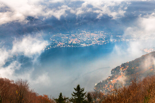 Clouds over the Como lake and autumn Alps mountains. Como, Italy. Beautiful autumn landscape at foggy morning