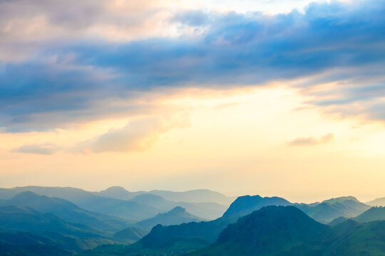 View of the green mountains and hills in the evening sunlight. Pink sky with blue clouds at sunset. Gumbashi pass in North Caucasus, Russia