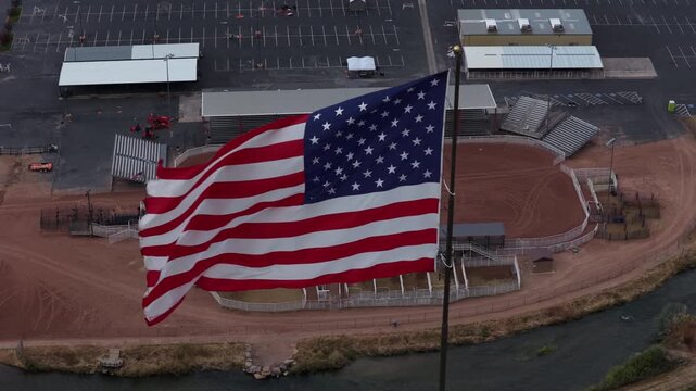 Aerial of American flag above rodeo arena and fairgrounds in small desert rural town Duchesne Utah