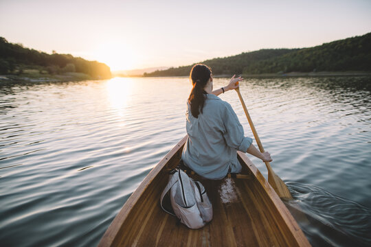 Rear view of woman canoeing on peaceful evening lake
