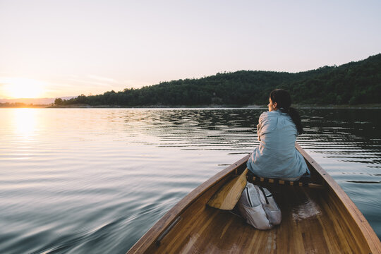 Rear view of woman sitting in canoe at golden hour, copy space