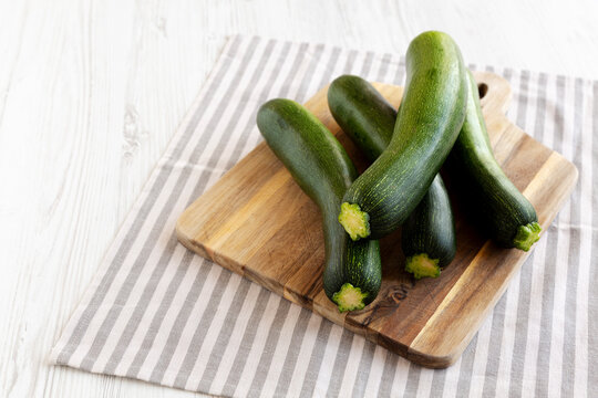 Raw Green Organic Zucchini on a Wooden Board, side view. Copy space.