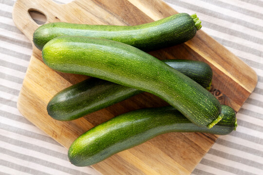 Raw Green Organic Zucchini on a Wooden Board, top view.