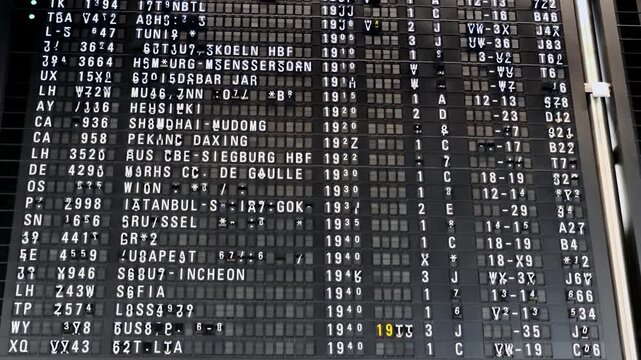 Split-flap mechanical departure board actively flipping alphanumeric tiles to update flight status and destination information at Frankfurt Airport