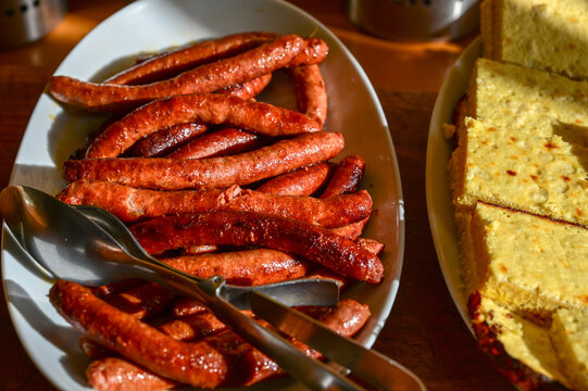 Pile of freshly fried sausages served on a buffet table in a restaurant. Delicious roasted sausages piled up at a restaurant catering service.