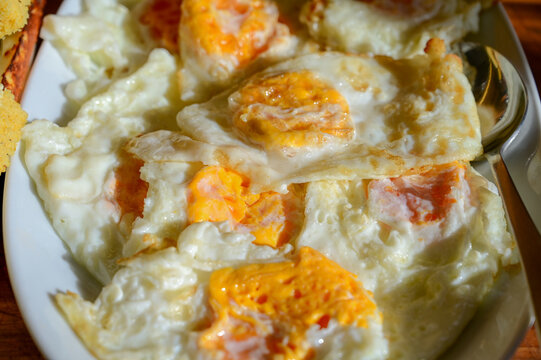 Batch of fried eggs with golden, slightly set yolks and crispy edges. Freshly cooked fried eggs in a pan with golden runny yolks.