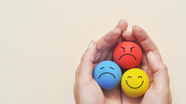 Hands that hold happy, sad, and angry emotions, symbolizing emotional balance.