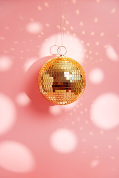 Gold disco mirror ball against a pink background
