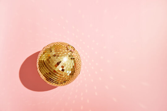 Gold disco mirror ball against a pink background