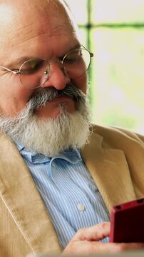 Indian Asian elderly businessman with a beard, dressed in a suit, using a laptop for work and messaging on his phone, efficiently balancing his work and personal life