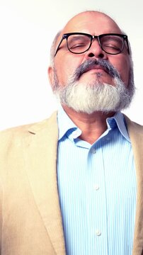 Indian Asian elderly businessman with beard, standing in a suit on white background, doing meditation with closed eyes and mudra hand gestures for mental peace and relaxation