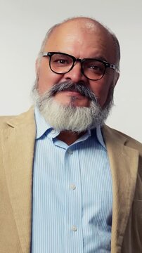 Indian Asian elderly businessman with a beard, standing in a suit on a white background, smiling with both fists raised, showing success and confidence 