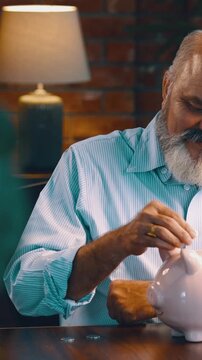 Indian Asian elderly businessman with beard, happily putting coins into a piggy bank and giving thumbs up with both hands, showing satisfaction and savings success
