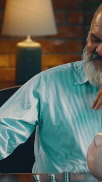 Indian Asian elderly businessman with beard, surrounded by coins and Indian currency notes, with a piggy bank on the table, smiling with satisfaction  on his money-saving efforts