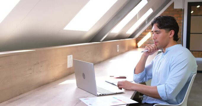 Man pausing pen-to-mouth at office shifting to laptop trackpad typing-checking charts, copy space