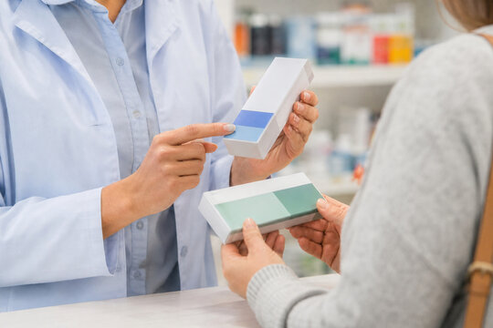 Pharmacist assists customer with medication, explaining product details for over-the-counter and prescription drug information in pharmacy setting.