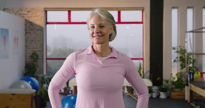 Camera zooming Senior woman standing in studio adjusting pose, crossing arms, smiling for close-up
