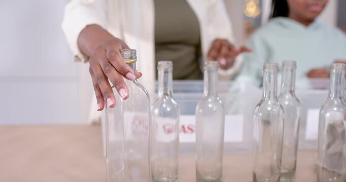 Parents and child seeing row of glass bottles, sorting into recycling bins at kitchen table