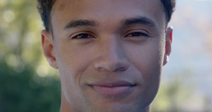African American man shifting from neutral face to smile then laughing in park with sunlit bokeh