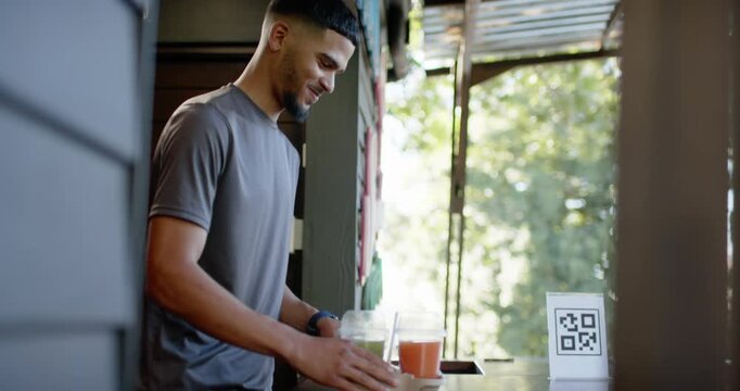 Male server placing two drinks customer handing card processing payment on reader at wooden counter