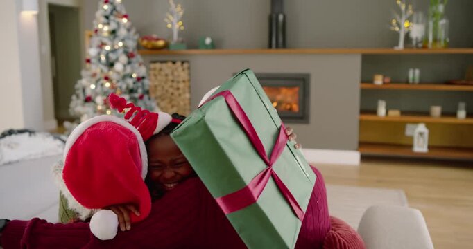African American child seeing parents Santa hats running home falling into hug giving green gift
