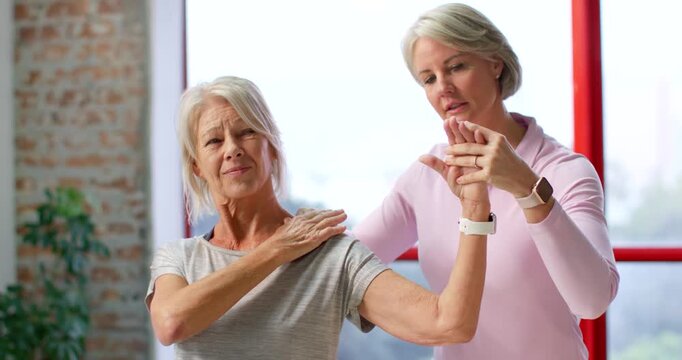 Senior woman and therapist after pain guiding arm rotation in clinic using hands for mobility