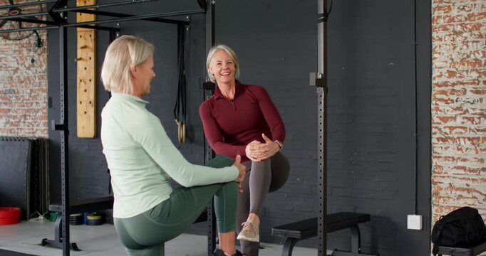 Senior women coach showing knee hug, partner stepping forward and training balance at gym rack