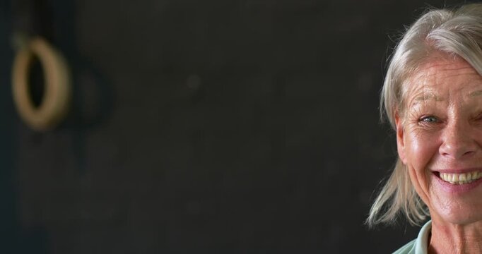 Mature woman reacting to cue, smiling, turning to camera by brick wall with ring, copy space