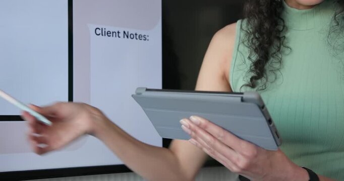 African American woman tapping tablet, pointing stylus at mockup for client in office, copy space