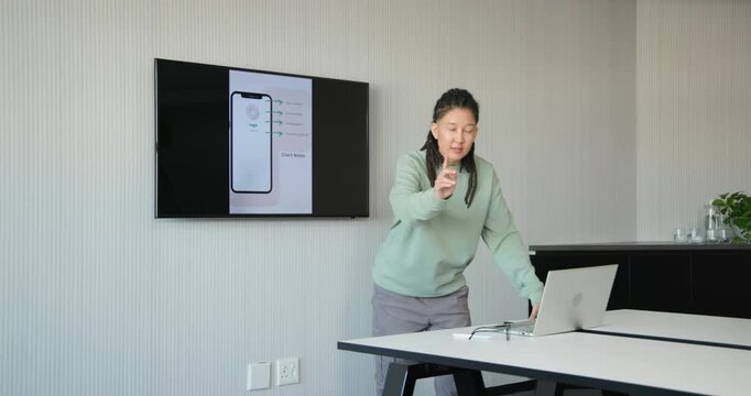 African American nonbinary presenter advancing slides pointing leaning showing phone UI in office