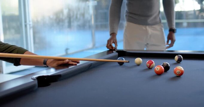 African American men spotting open shot, lining up and striking cue ball at blue-felt pool table