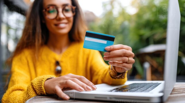 A Woman is Holding a Credit Card While She is Shopping Online on Her Laptop Computer at Home or Outdoors