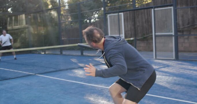 Opponent hitting ball, two men near swinging black racket returning ball on padel court, copy space