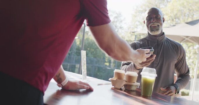 Customer tapping phone, confirming payment, barista handing drinks at cafe counter, copy space