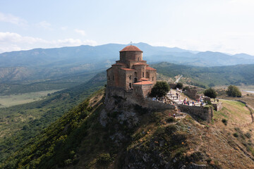 Fototapeta premium Ancient stone church standing on a rocky promontory above a picturesque mountainous valley
