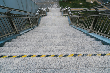 Obraz premium Outdoor staircase with cautious atmosphere showing granite steps and metal railing for safety, urban architectural detail perspective