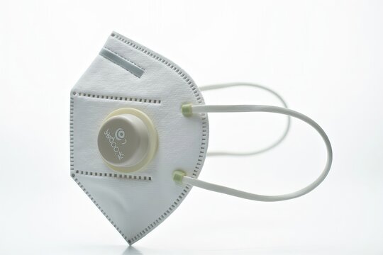 White medical respiratory face mask with filter in close-up, on white background.